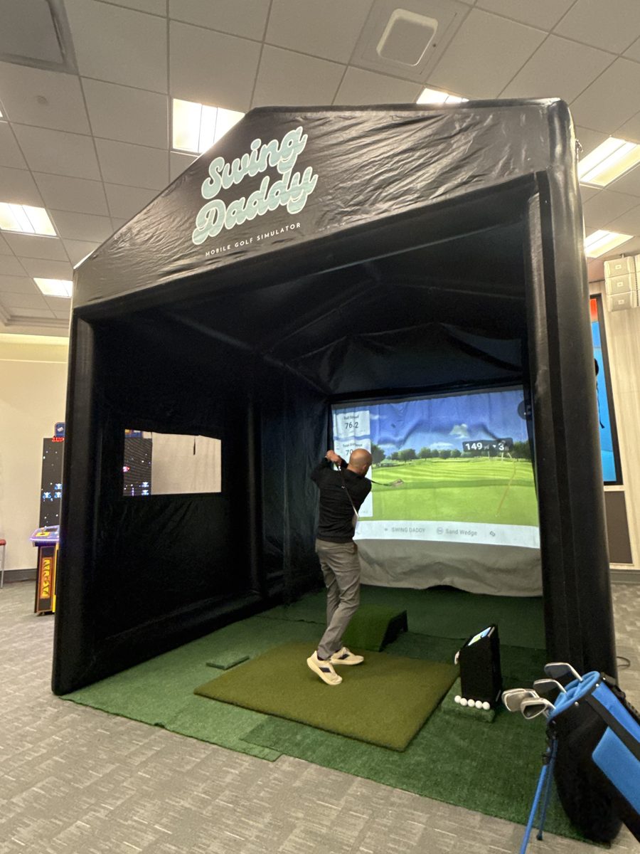 Guest mid-swing at the Swing Daddy mobile golf simulator at an Oklahoma event
